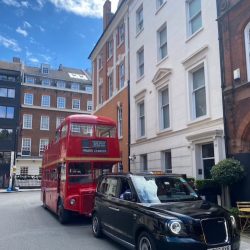 A red London bus and black London taxi parked on Hertford Street in London.