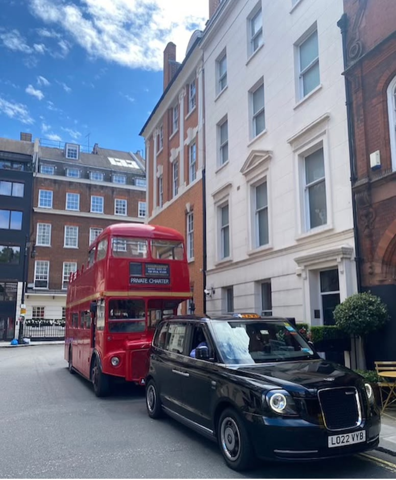 A red London bus and black London taxi parked on Hertford Street in London.