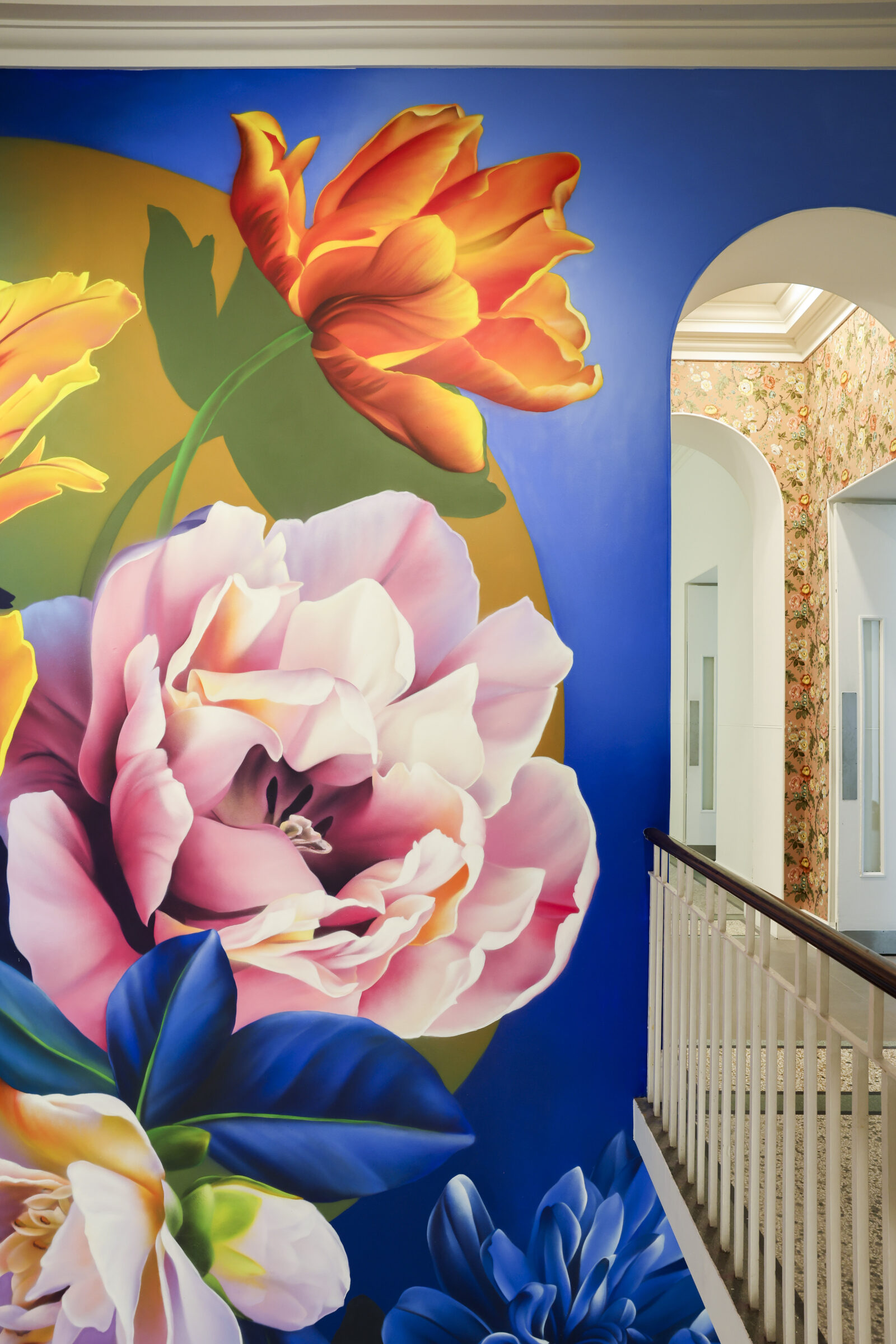 Sophie Mess's mural at the stairway of the Saatchi Gallery, where she has painted bold yellow, pink and red flowers against a royal blue backdrop.