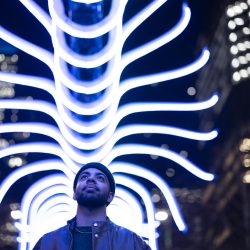 A visitor walking under a light installation at the Canary Wharf Winter Lights Festival 2025.