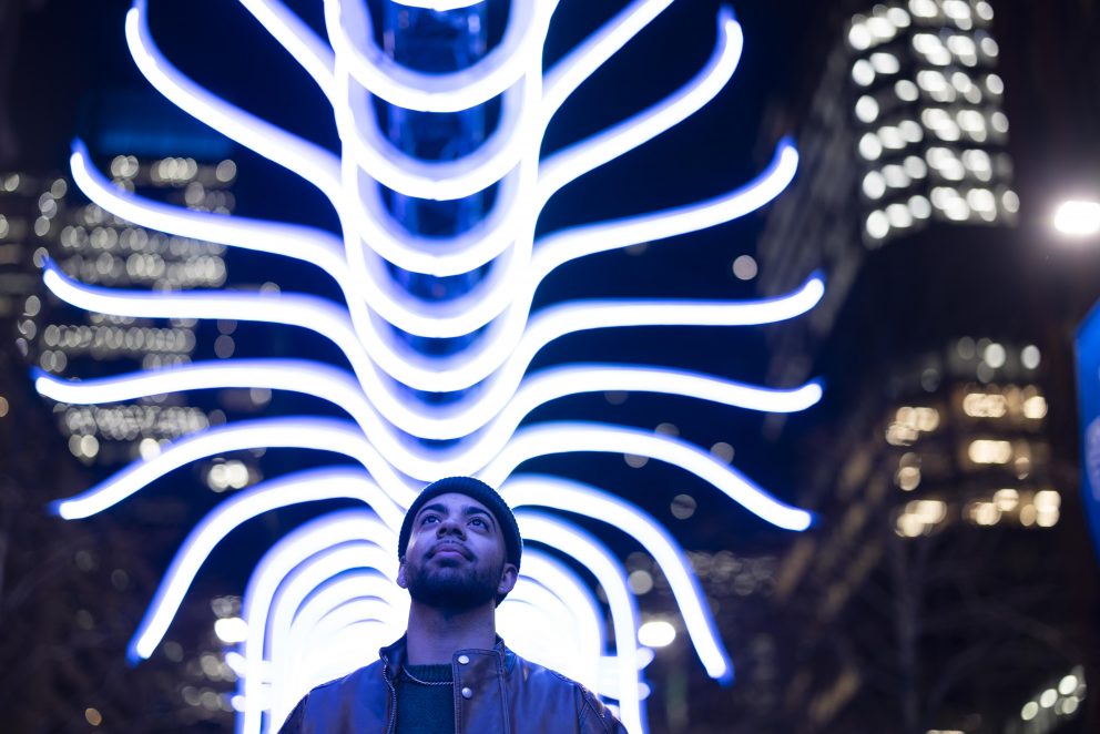 A visitor walking under a light installation at the Canary Wharf Winter Lights Festival 2025.