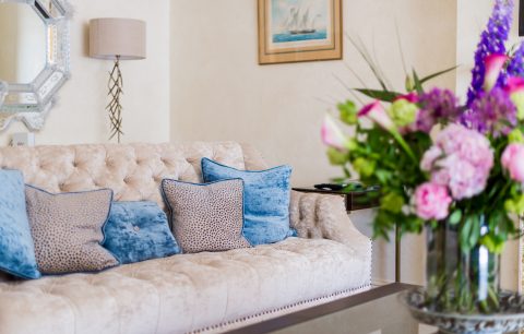 The living area of an apartment at 9 Hertford Street, Mayfair with a cushion filled settee in the background and a beautiful display of flowers on the coffee table.