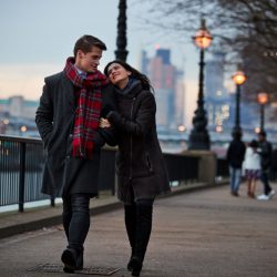 A man and a woman walking in London, dressed in winter clothing.