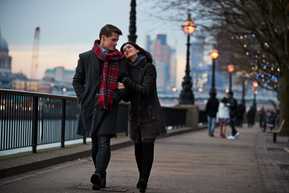 A man and a woman walking in London, dressed in winter clothing.