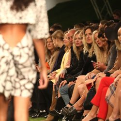 A model on the catwalk at London Fashion Week with front row spectators looking on.