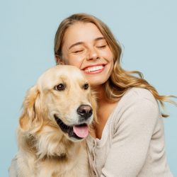 A young woman cuddling a golden retriever dog.