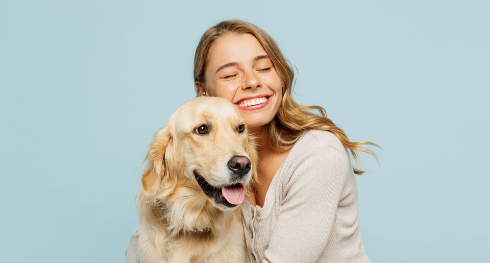 A young woman cuddling a golden retriever dog.