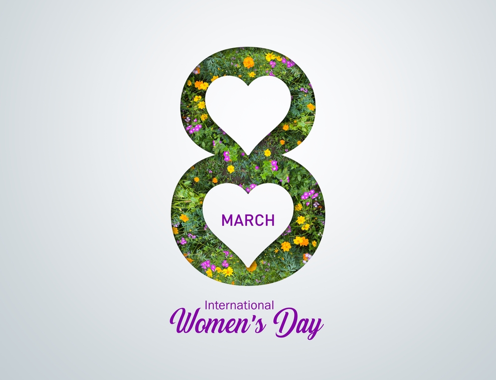 The silhouette of an 8 in flowers with a white background and the two centres of the figure of 8 cut out in white hearts. March is capitalised in purple in the lower heart, and International Women's Day is printed in purple below the 8.