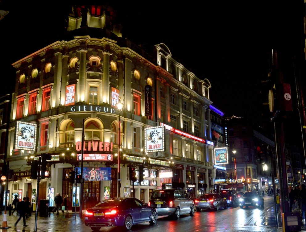 The exterior of the Gielgud Theatre in London at nighttime, with passing traffic.